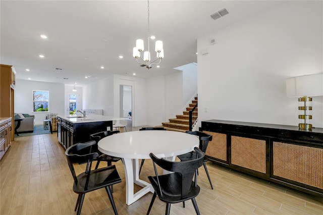 dining area featuring an inviting chandelier, sink, and light hardwood / wood-style floors