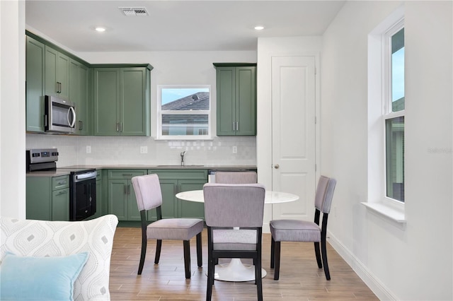 kitchen with stainless steel appliances, tasteful backsplash, sink, and green cabinets