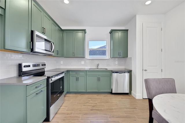 kitchen featuring sink, stainless steel appliances, green cabinetry, and light wood-type flooring