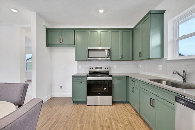 kitchen with tasteful backsplash, green cabinets, stainless steel appliances, and sink