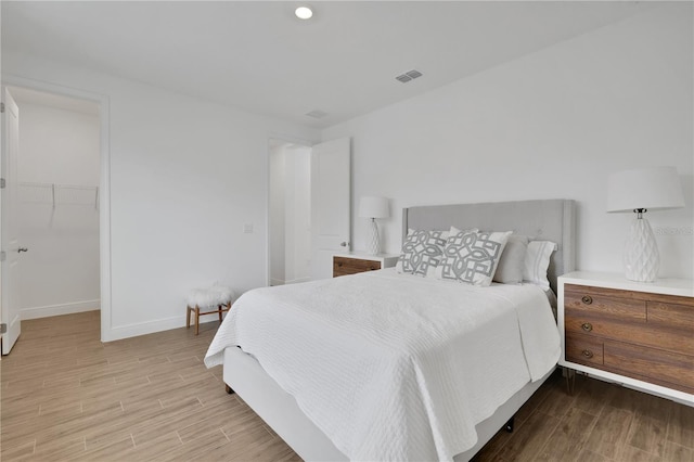 bedroom featuring a walk in closet and light hardwood / wood-style floors