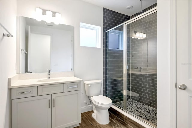 bathroom featuring toilet, vanity, and a shower with shower door