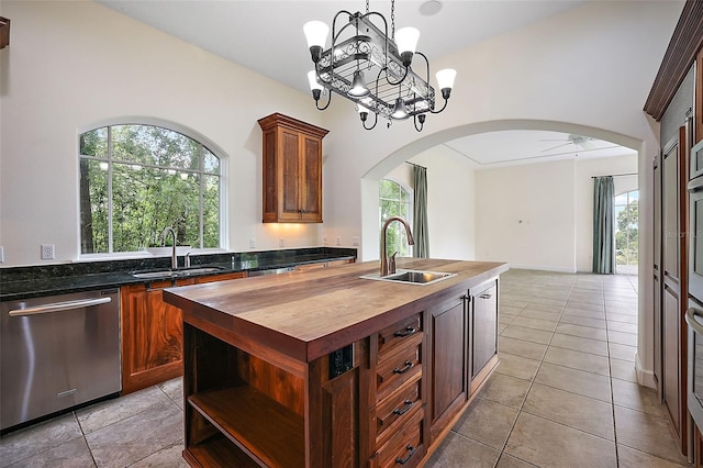 kitchen with ceiling fan with notable chandelier, sink, light tile floors, stainless steel dishwasher, and pendant lighting