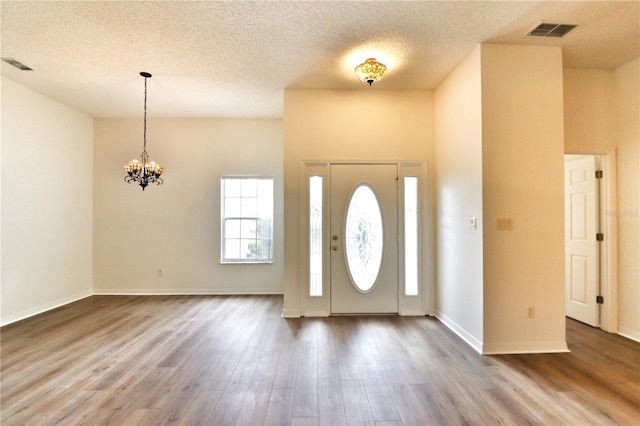 entrance foyer featuring hardwood / wood-style floors, a textured ceiling, and an inviting chandelier