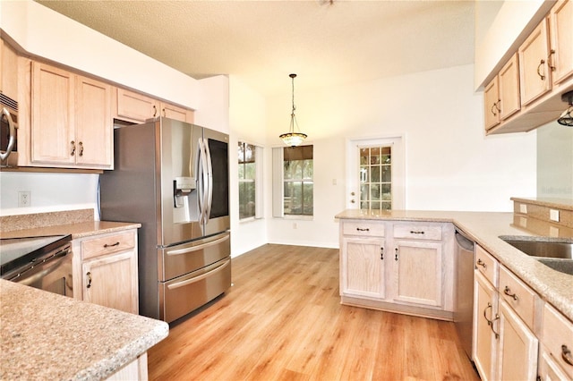 kitchen featuring pendant lighting, light brown cabinets, appliances with stainless steel finishes, and light hardwood / wood-style flooring