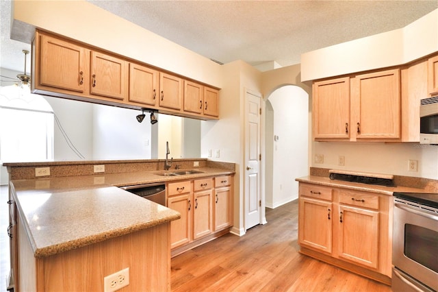 kitchen featuring sink, a textured ceiling, light brown cabinetry, appliances with stainless steel finishes, and light wood-type flooring