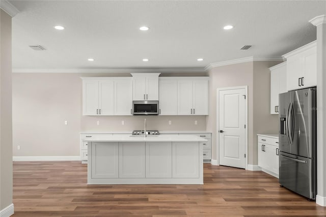 kitchen featuring white cabinetry, ornamental molding, wood-type flooring, and appliances with stainless steel finishes