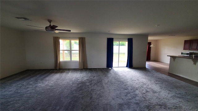 empty room with ceiling fan and dark colored carpet