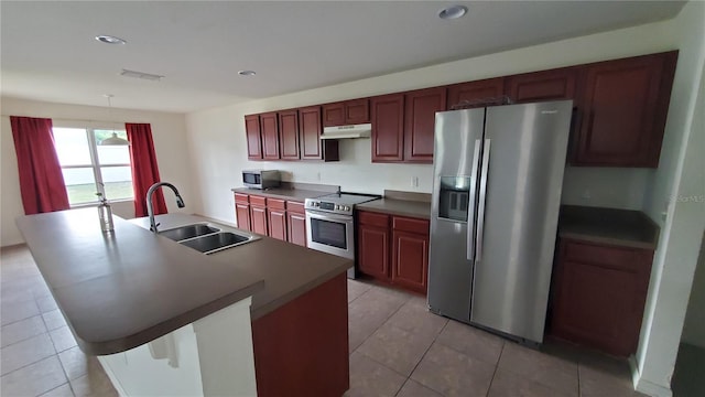 kitchen featuring an island with sink, tile flooring, sink, and stainless steel appliances