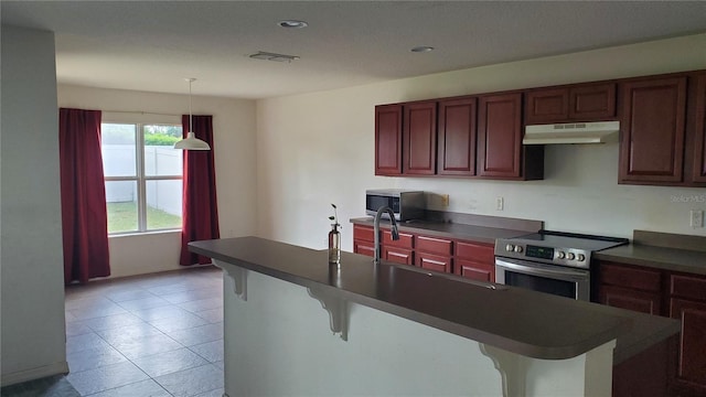 kitchen with decorative light fixtures, light tile flooring, appliances with stainless steel finishes, a breakfast bar, and sink