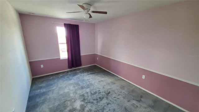 spare room featuring dark carpet and ceiling fan