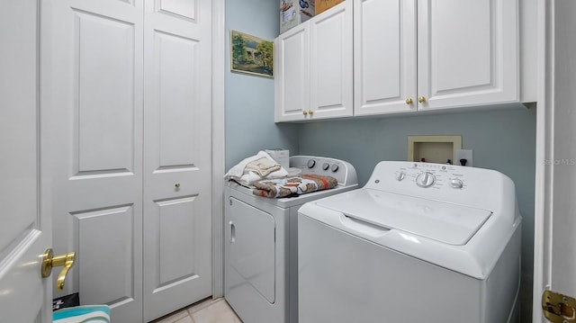 clothes washing area with cabinets, light tile patterned floors, and washing machine and clothes dryer