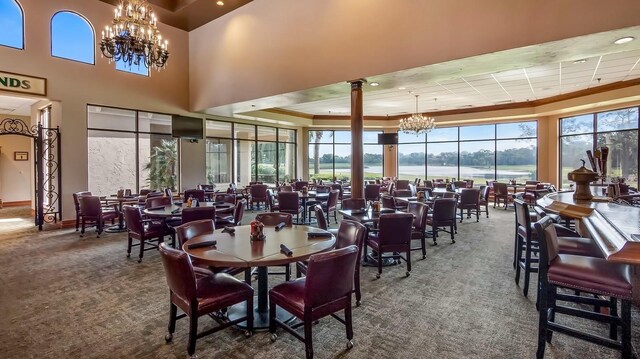 dining area with decorative columns, carpet, and an inviting chandelier