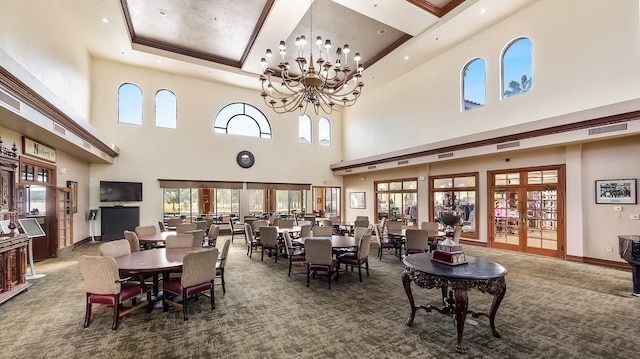 carpeted dining space featuring an inviting chandelier, a towering ceiling, plenty of natural light, and a raised ceiling