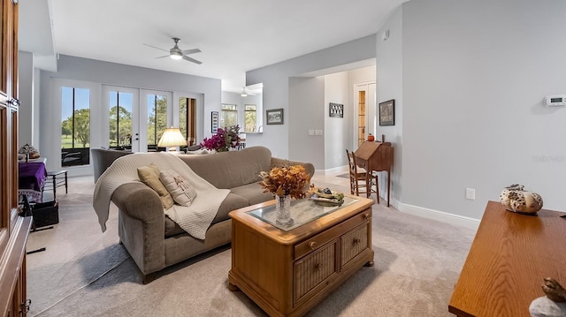 living room with french doors, ceiling fan, and light colored carpet