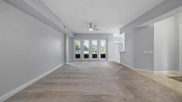 unfurnished living room featuring light carpet, french doors, and ceiling fan