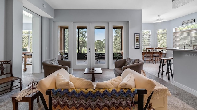 interior space featuring a wealth of natural light, light colored carpet, ceiling fan, and french doors