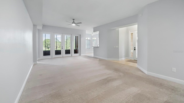 unfurnished living room with light colored carpet and ceiling fan