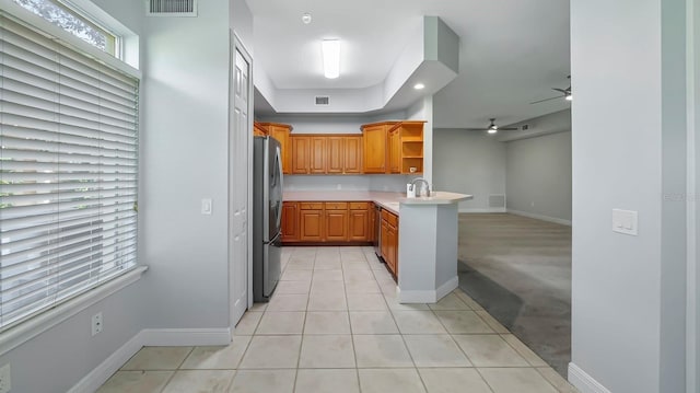 kitchen featuring light tile patterned floors, sink, stainless steel refrigerator, ceiling fan, and kitchen peninsula