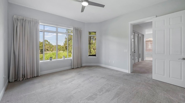 carpeted spare room featuring a healthy amount of sunlight and ceiling fan