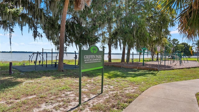 view of home's community with a playground, a water view, and a yard