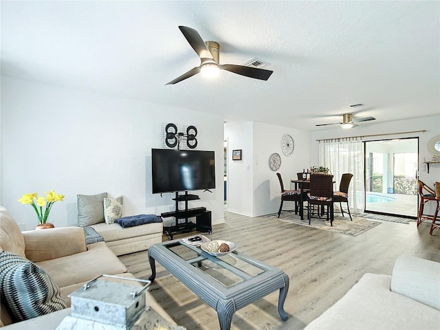 living room featuring a textured ceiling, light hardwood / wood-style floors, and ceiling fan