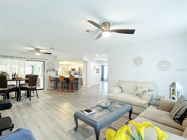 living room featuring ceiling fan and light hardwood / wood-style flooring