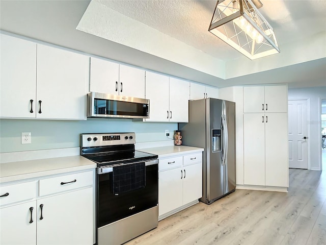 kitchen featuring appliances with stainless steel finishes, light wood-type flooring, a textured ceiling, and white cabinetry