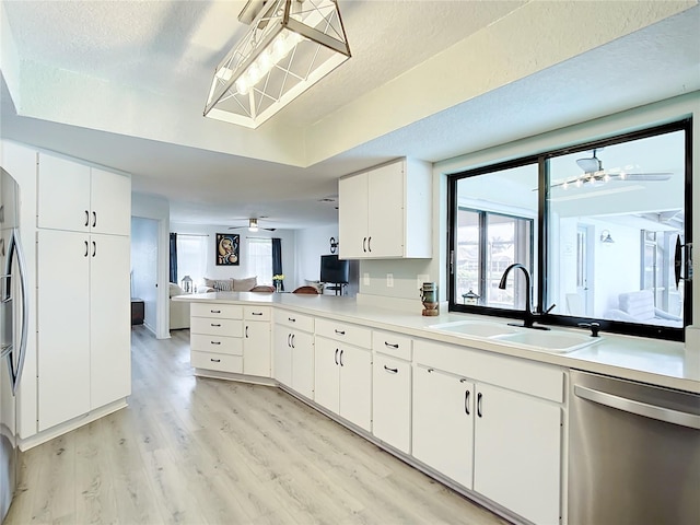 kitchen with dishwasher, sink, hanging light fixtures, light wood-type flooring, and white cabinetry