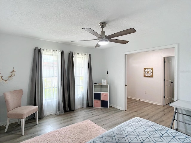 bedroom with a textured ceiling, light wood-type flooring, and ceiling fan