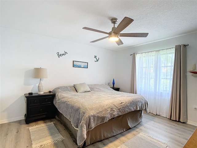 bedroom with a textured ceiling, light wood-type flooring, and ceiling fan