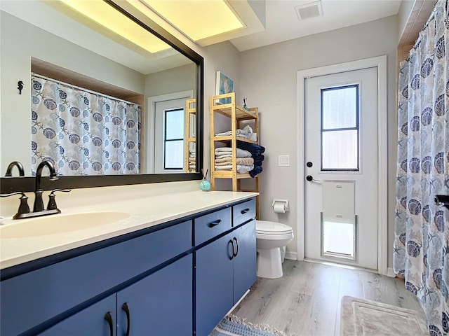 bathroom with walk in shower, hardwood / wood-style floors, vanity, and toilet