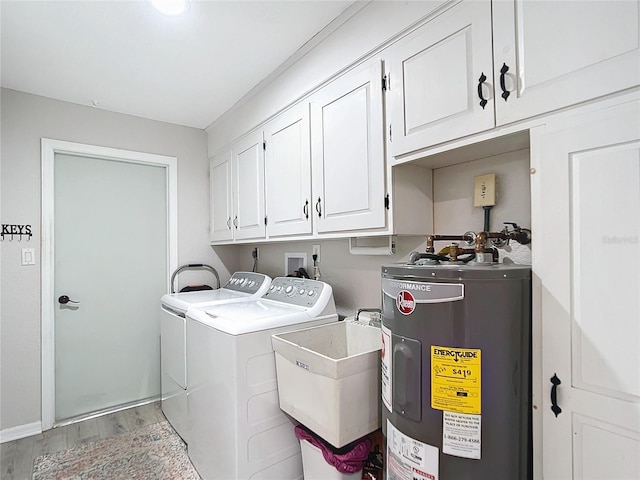 clothes washing area with washing machine and clothes dryer, sink, cabinets, electric water heater, and light hardwood / wood-style flooring