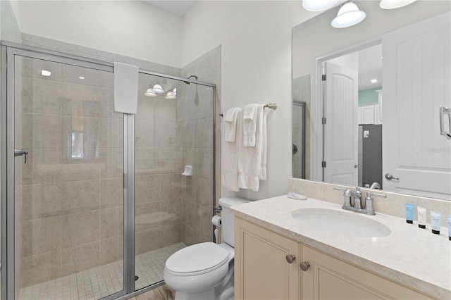 bathroom featuring toilet, vanity, and an enclosed shower