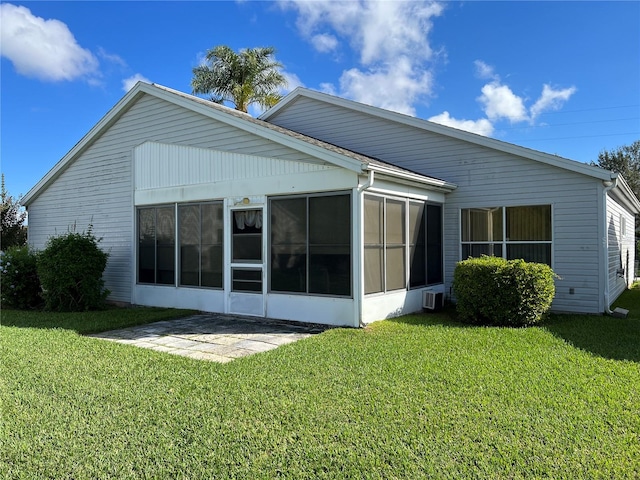 rear view of house featuring a yard and a sunroom