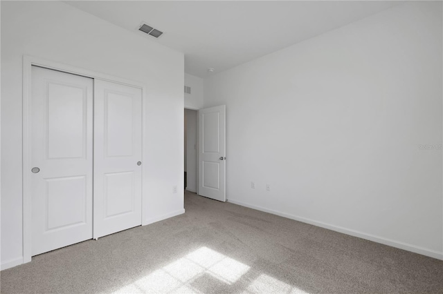 unfurnished bedroom featuring a closet and light colored carpet