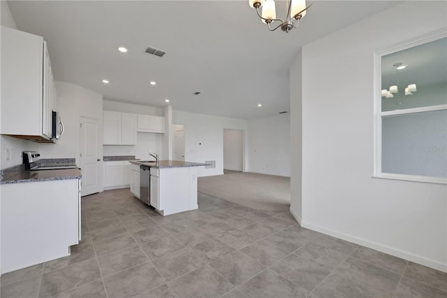 kitchen with white cabinets, a notable chandelier, sink, a kitchen island with sink, and appliances with stainless steel finishes