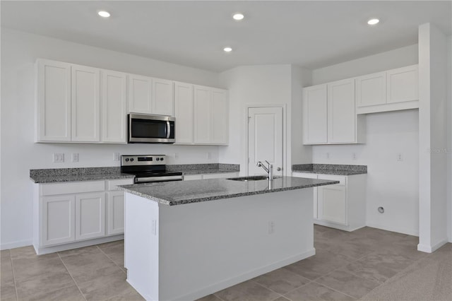 kitchen featuring stainless steel appliances, white cabinets, sink, a kitchen island with sink, and dark stone countertops