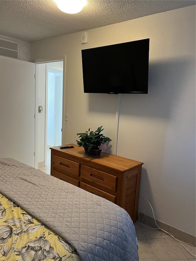 bedroom featuring visible vents, baseboards, light tile patterned flooring, and a textured ceiling