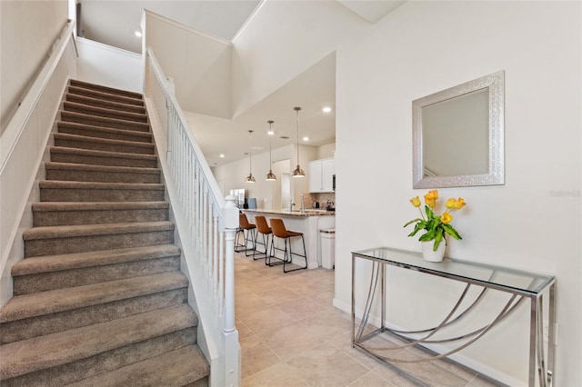 stairs with light tile floors and a towering ceiling