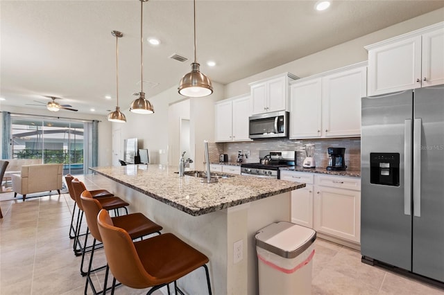 kitchen featuring light stone countertops, hanging light fixtures, white cabinetry, ceiling fan, and appliances with stainless steel finishes