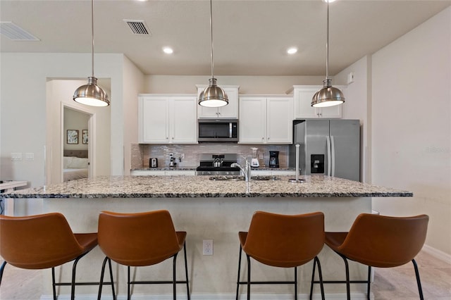 kitchen with appliances with stainless steel finishes, tasteful backsplash, and a breakfast bar area