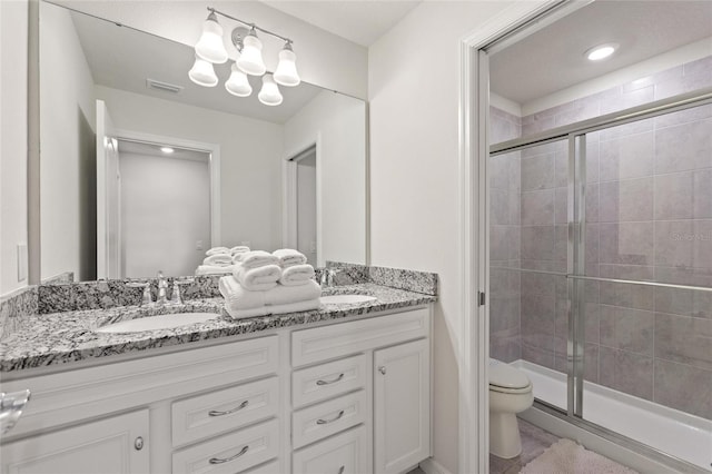 bathroom with walk in shower, oversized vanity, dual sinks, and toilet