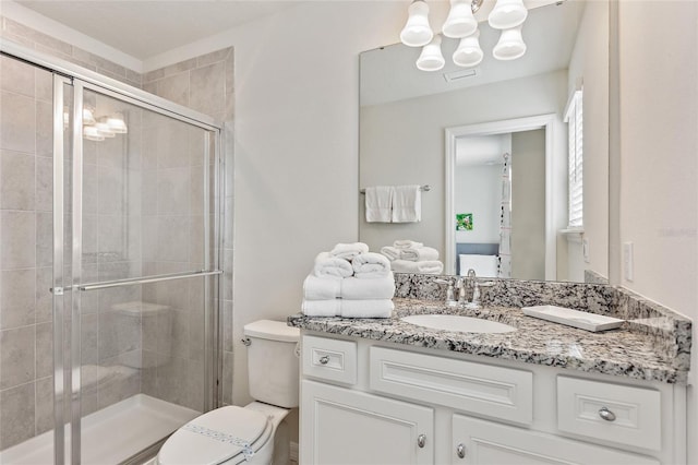 bathroom featuring an enclosed shower, toilet, vanity, and a notable chandelier