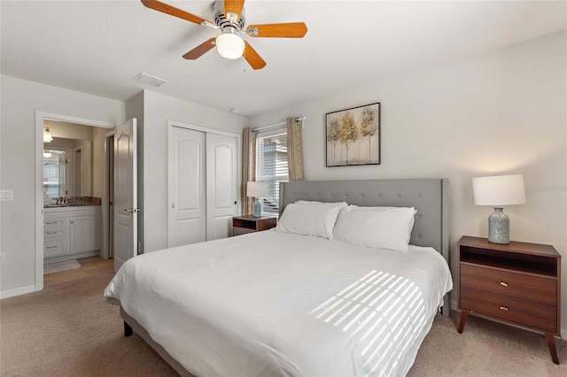 carpeted bedroom featuring a closet, connected bathroom, and ceiling fan