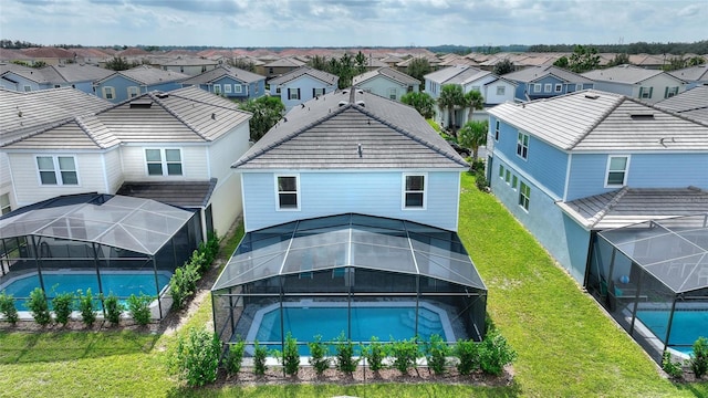 back of property with a fenced in pool, a lanai, and a yard