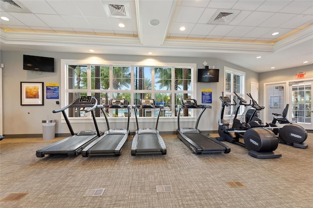 gym with carpet, a tray ceiling, and a wealth of natural light