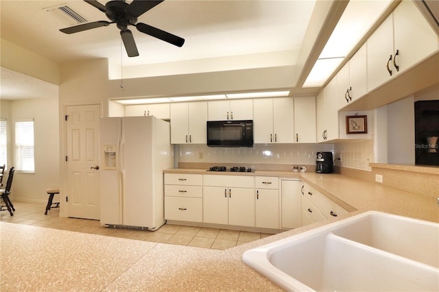 kitchen with light tile floors, white cabinets, backsplash, and white refrigerator with ice dispenser