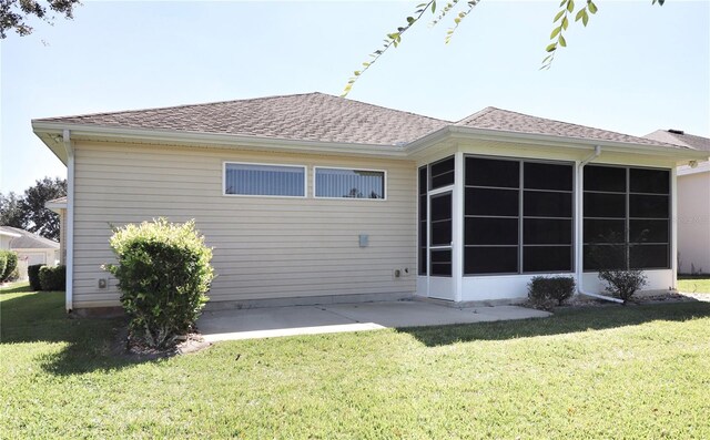 rear view of property with a yard, a sunroom, and a patio