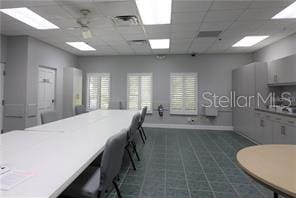 interior space with tile floors, ceiling fan, and a paneled ceiling